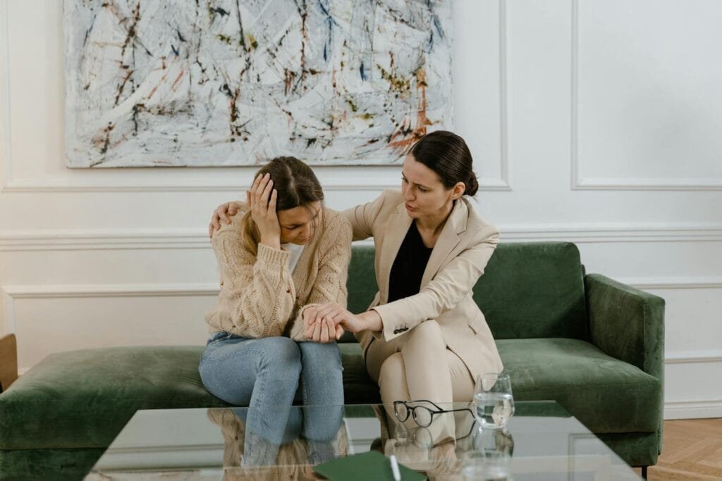 7699529 A therapy session where a concerned therapist supports a distressed woman in a modern office.